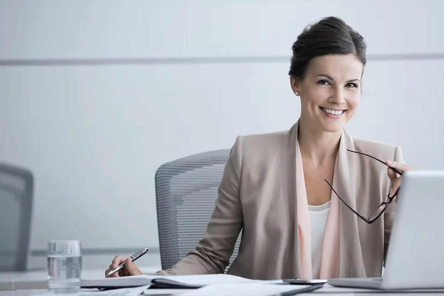 A smiling HR leader in a beige blazer at her desk